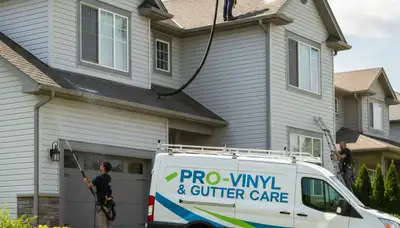 Technician cleaning home gutters in Greenville, NC for Next Level Exteriors vinyl siding service